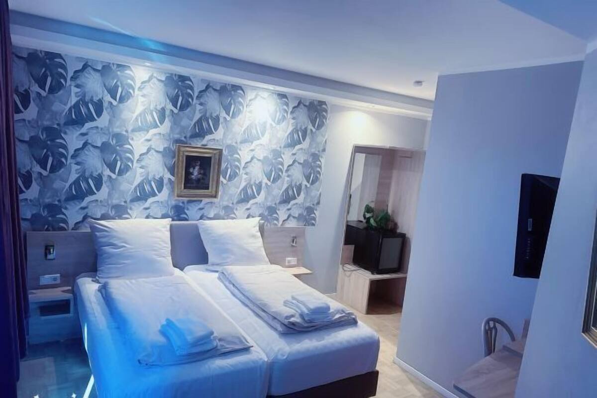 Una habitación de hotel moderna con una cama grande, un televisor y un escritorio con silla.