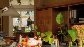 A reception desk with a decorative ceramic cat, a potted plant, and a hanging light fixture.