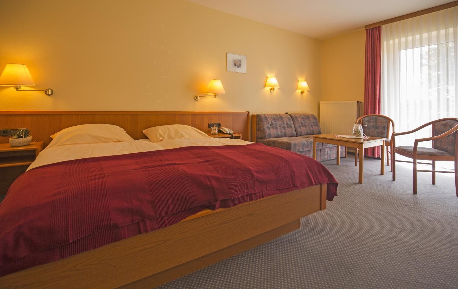 Una habitación de hotel con una cama grande, un escritorio, dos sillas y un sofá.