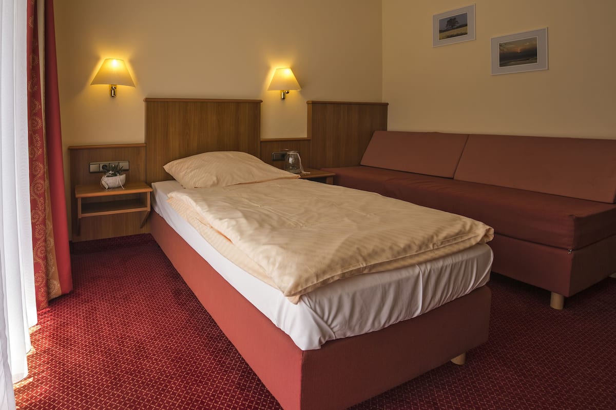 Ein Hotelzimmer mit einem Bett, einer Couch, zwei Nachttischlampen, einem Nachttisch und einem kleinen Tisch.