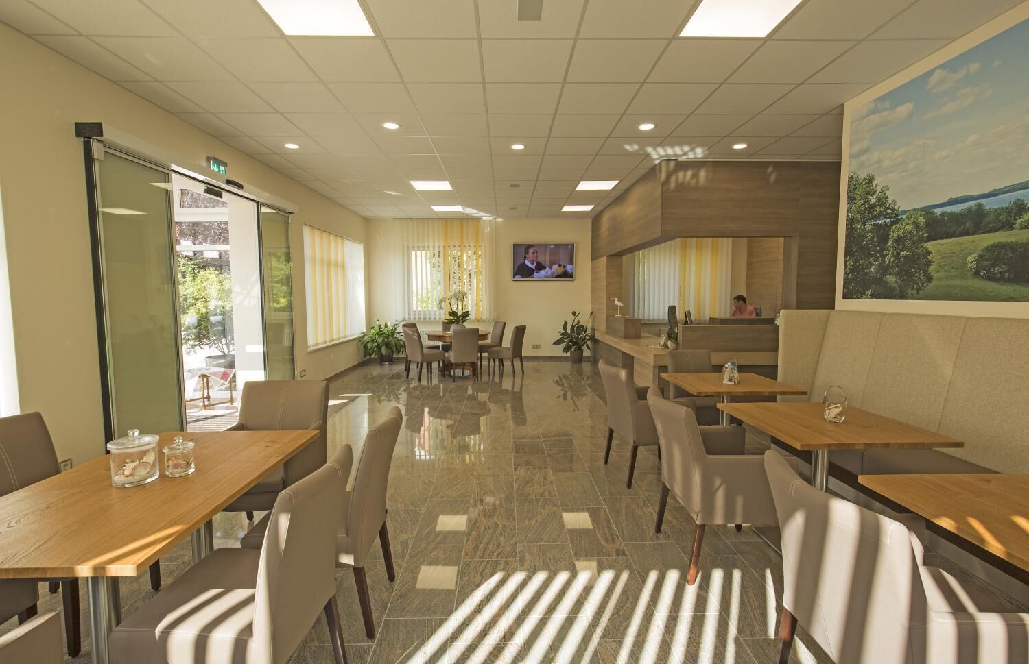 A modern conference room with glass walls, a large screen, and a dining area with tables and chairs.
