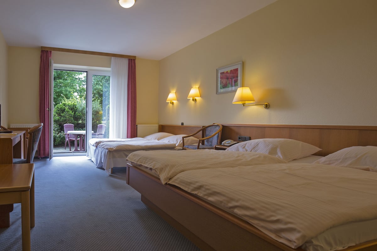 Ein Hotelzimmer mit zwei Betten, einem Schreibtisch, einem Stuhl und Blick ins Freie.