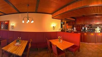 A restaurant with wooden tables and booths, a curved ceiling, and wall-mounted lighting.