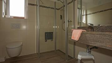 A modern bathroom with a glass-enclosed shower, a toilet, and a vanity with a granite countertop.