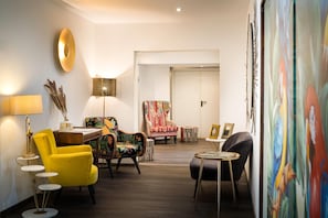 A modern living room with a yellow armchair, a patterned armchair, a small round table, and a lamp. - Arthotel ANA Eden Karlsruhe, Trademark Collection by Wyndham (Karlsruhe)