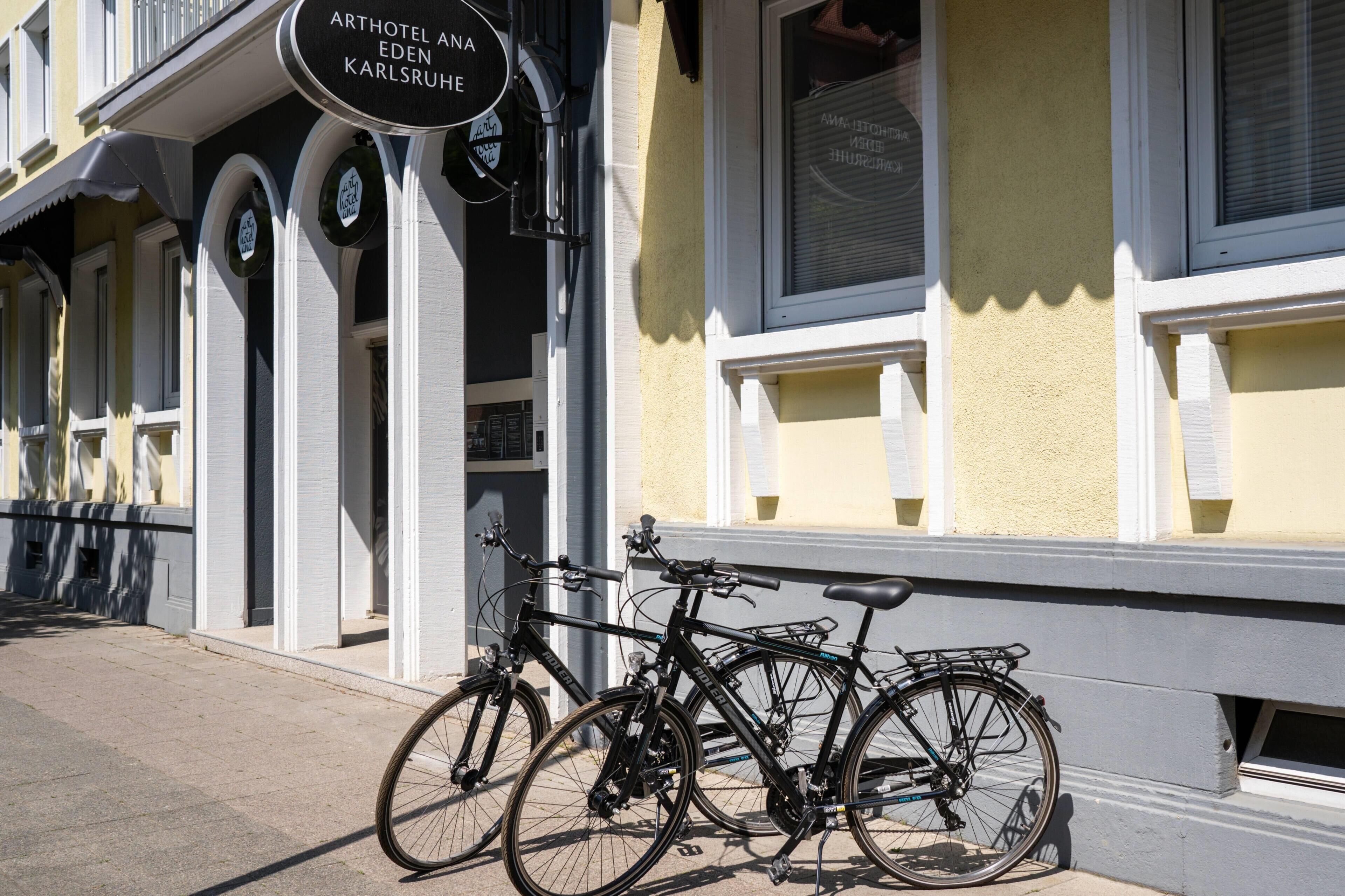 Una bicicleta estacionada frente a un edificio con un cartel que dice 'ARTHOTEL ANA EDEN KARLSRUHE'.