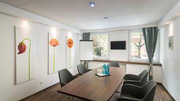 A conference room with a wooden table, black chairs, and artwork on the walls.