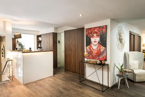 En moderne stue med et køkkenområde, et spisebord og et stort maleri på væggen.