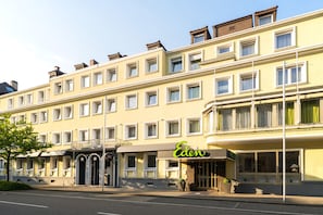 A multi-story hotel with a yellow facade, large windows, and a green sign for the Eden hotel. - Arthotel ANA Eden Karlsruhe, Trademark Collection by Wyndham (Karlsruhe)