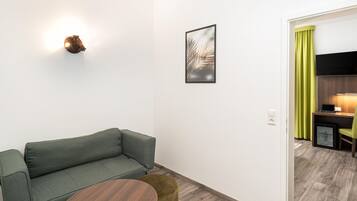 Una sala de estar moderna con un sofá, una mesita redonda, una lámpara de pared y un cuadro enmarcado.