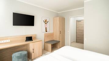 Un dormitorio moderno con cama, escritorio, silla y armario.
