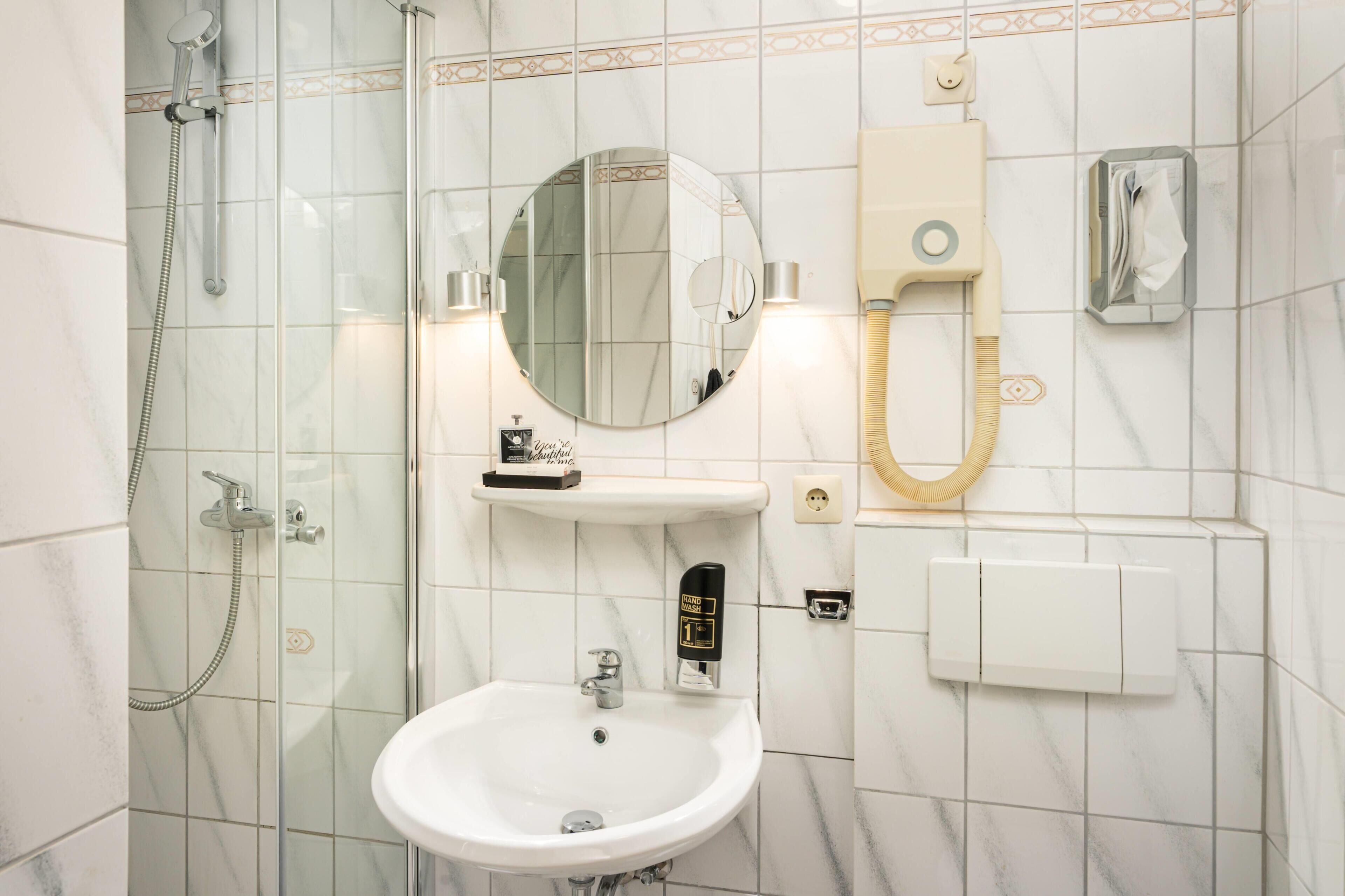 A bathroom with a glass-enclosed shower, a sink, a mirror, and a towel rack.