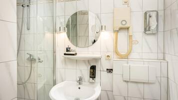 A bathroom with a glass-enclosed shower, a sink, a mirror, and a towel rack.