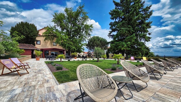 A courtyard with outdoor seating, a building with a red roof, and a clear sky. - Hotel Tenner (Neustadt an der Weinstrasse)