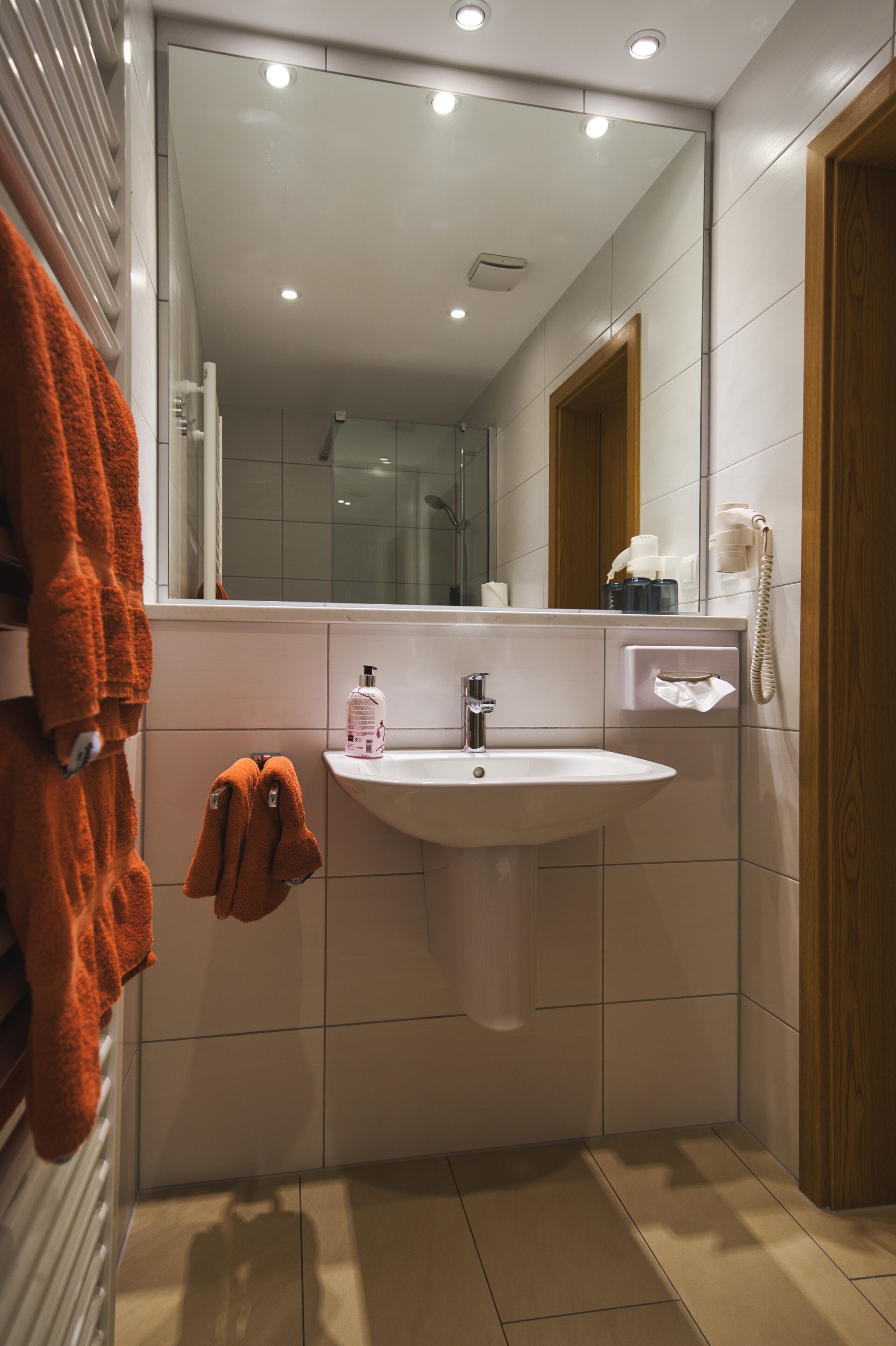 A modern bathroom with a white sink, a mirror, and a towel rack.