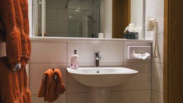 A modern bathroom with a white sink, a mirror, and a towel rack.