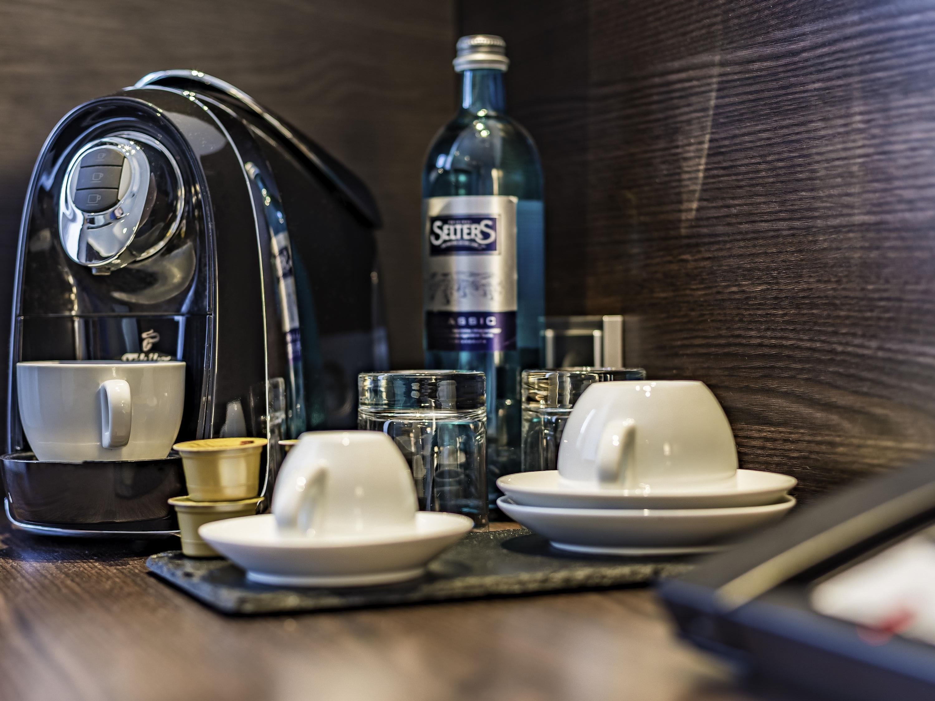 A coffee maker, a bottle of water, and a tea set on a table.