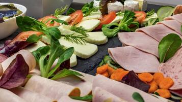 Variedad de alimentos como carnes, quesos y verduras dispuestas sobre una tabla de pizarra.