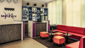 A reception area with a bar, seating, and clocks on the wall. - Mercure Hotel Frankfurt City Messe (Frankfurt)
