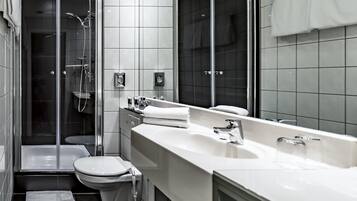 Un baño moderno con ducha envuelta en vidrio, inodoro y tocador con un espejo grande.