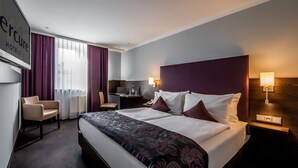 A hotel room with a large bed, a desk, a chair, and a TV. - Mercure Hotel Frankfurt City Messe (Frankfurt)