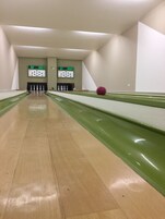 Un bowling avec des pistes vertes et un tableau d’affichage numérique.