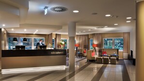 A hotel reception area with a reception desk, seating area, and large windows. - relexa hotel Harz-Wald (Braunlage)