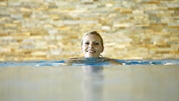 A person in a swimming pool with a stone wall in the background.