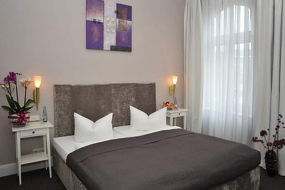 Ein Hotelzimmer mit einem großen Bett, zwei Nachttischen und einem Bild an der Wand.
