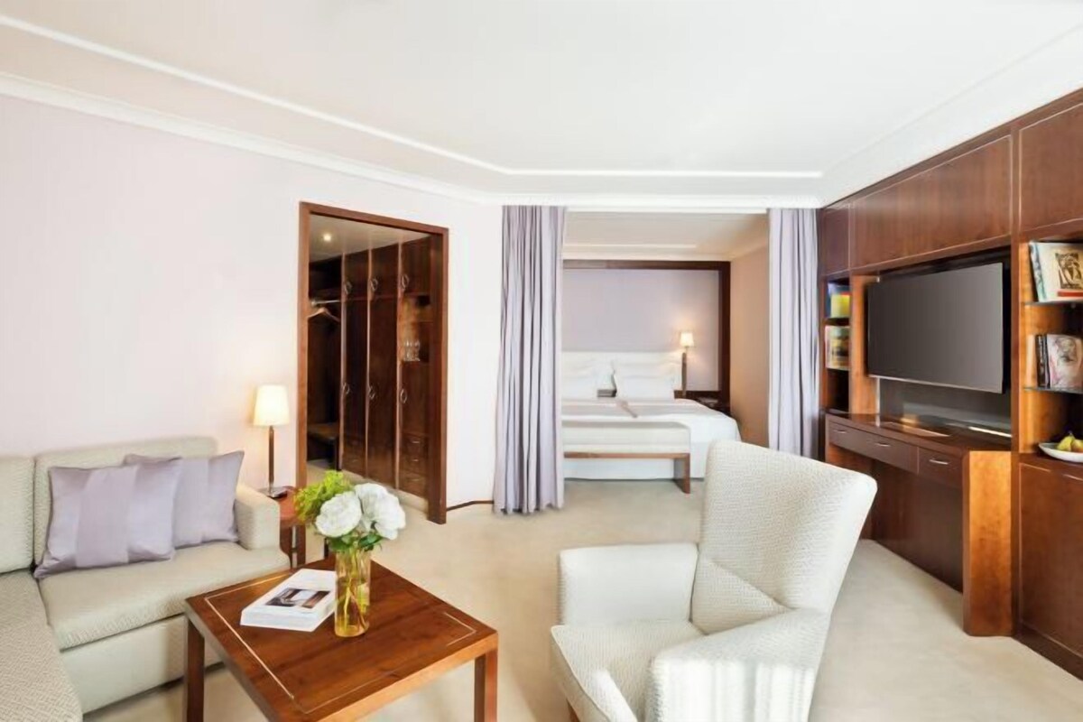 Una habitación de hotel con cama, sofá, televisor y un mueble de madera.