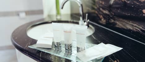 A bathroom sink with three Grand Elysée skincare products and a tissue.