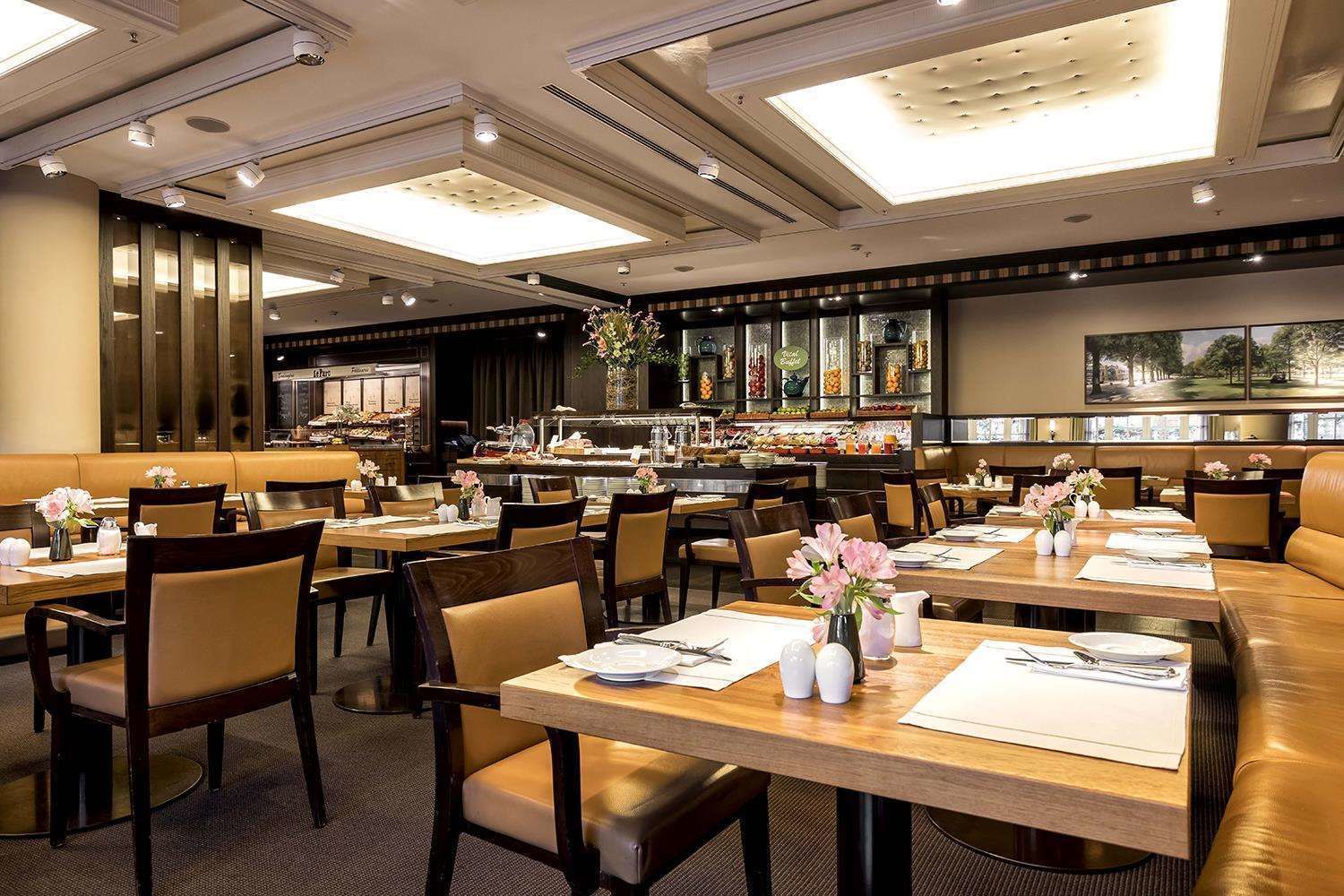 Un restaurante espacioso con varias mesas, cabinas acolchadas y una zona de bufé.