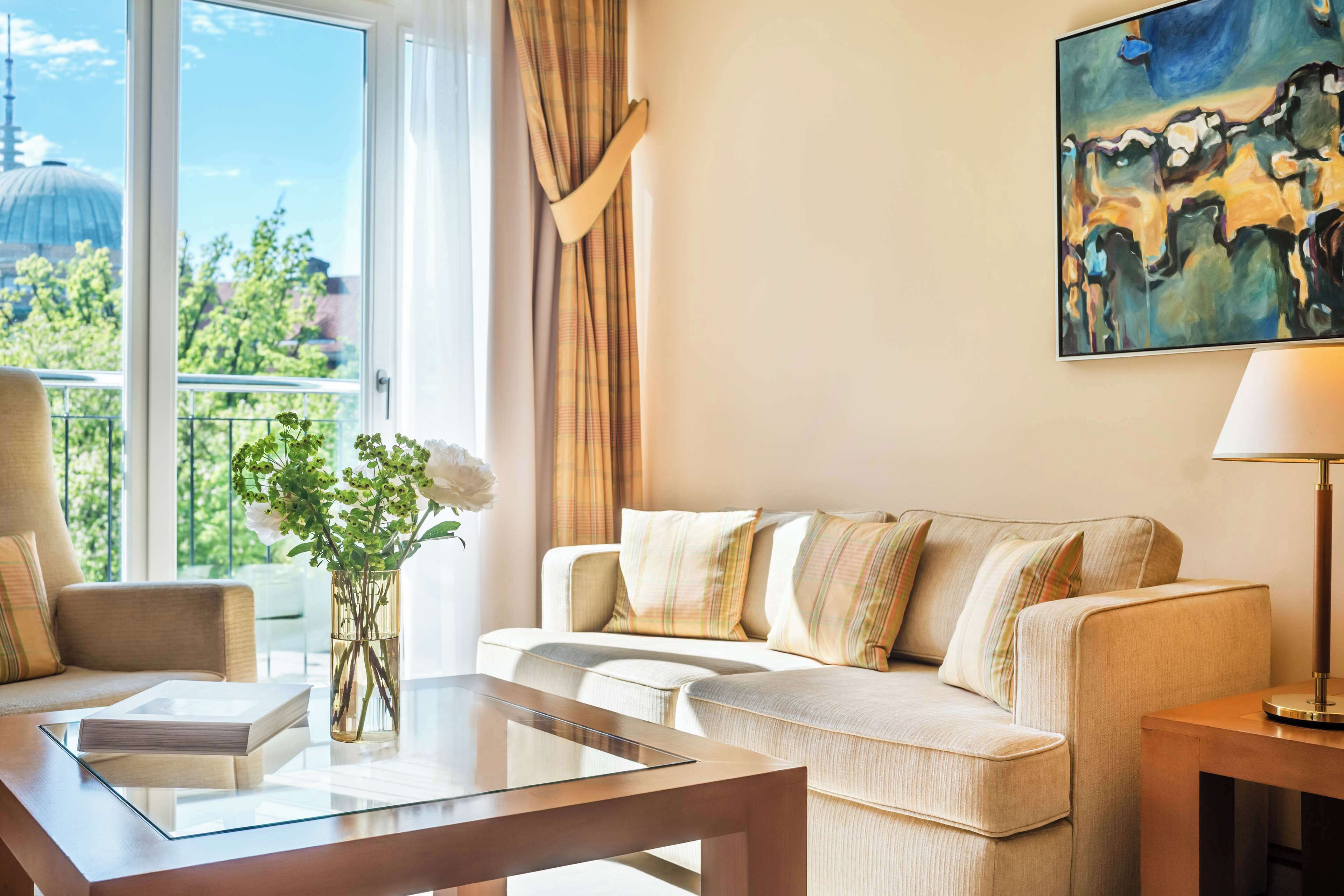 A modern living room with a sofa, a glass coffee table, and a painting on the wall.