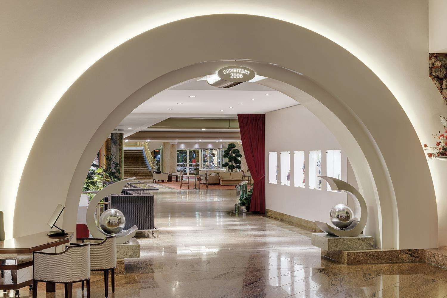 Un lobby amplio con un gran arco, una recepción y una escalera que conduce a los pisos superiores.