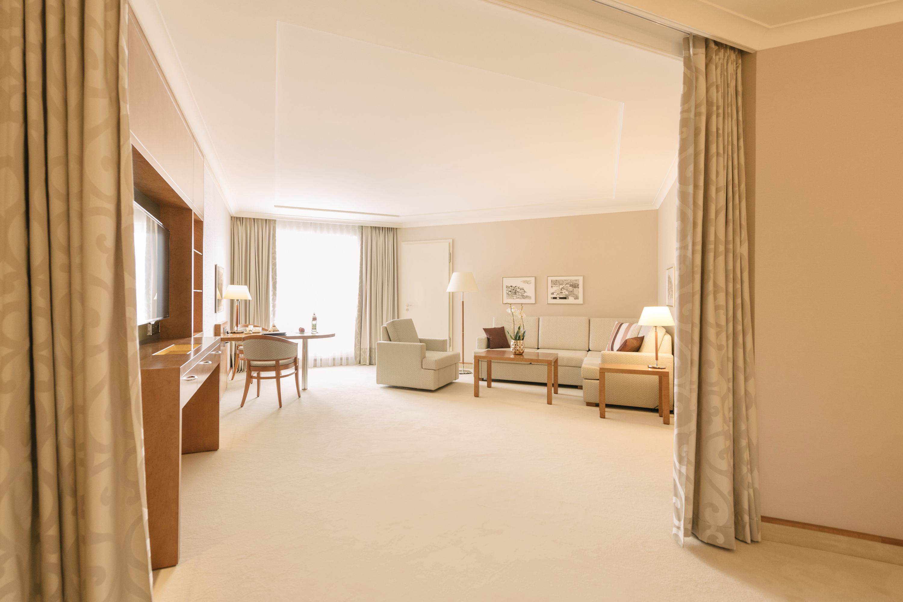 Una habitación de hotel amplia con un escritorio, dos sillones, un sofá y una mesa de centro.