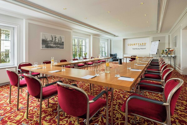 A conference room with a long table, red chairs, and a whiteboard.