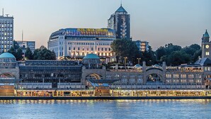 A waterfront hotel with a prominent tower and a large building with a dome. - Hotel Hafen Hamburg (Hamburg)
