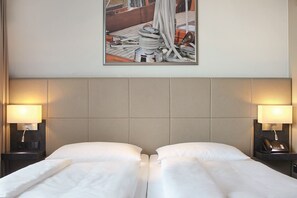 Une chambre d’hôtel avec un grand lit, deux tables de chevet avec des lampes et un tableau encadré au mur.