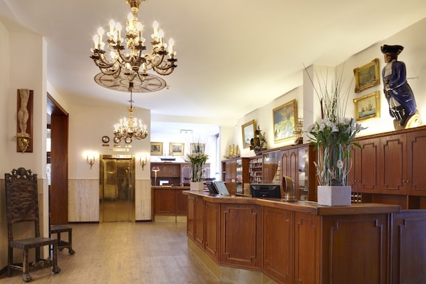 Eine großzügige Lobby mit einem prächtigen Kronleuchter, Holzvertäfelung und einer Rezeption.
