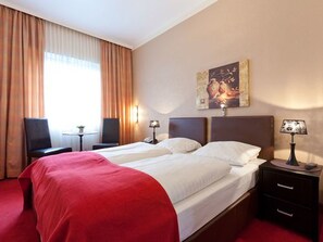A hotel room with two beds, a desk, a chair, and a painting on the wall. - Hotel Imperial Hamburg (Hamburg)