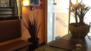 A reception area with a marble counter, a potted plant, a bench, and a glass door leading outside.