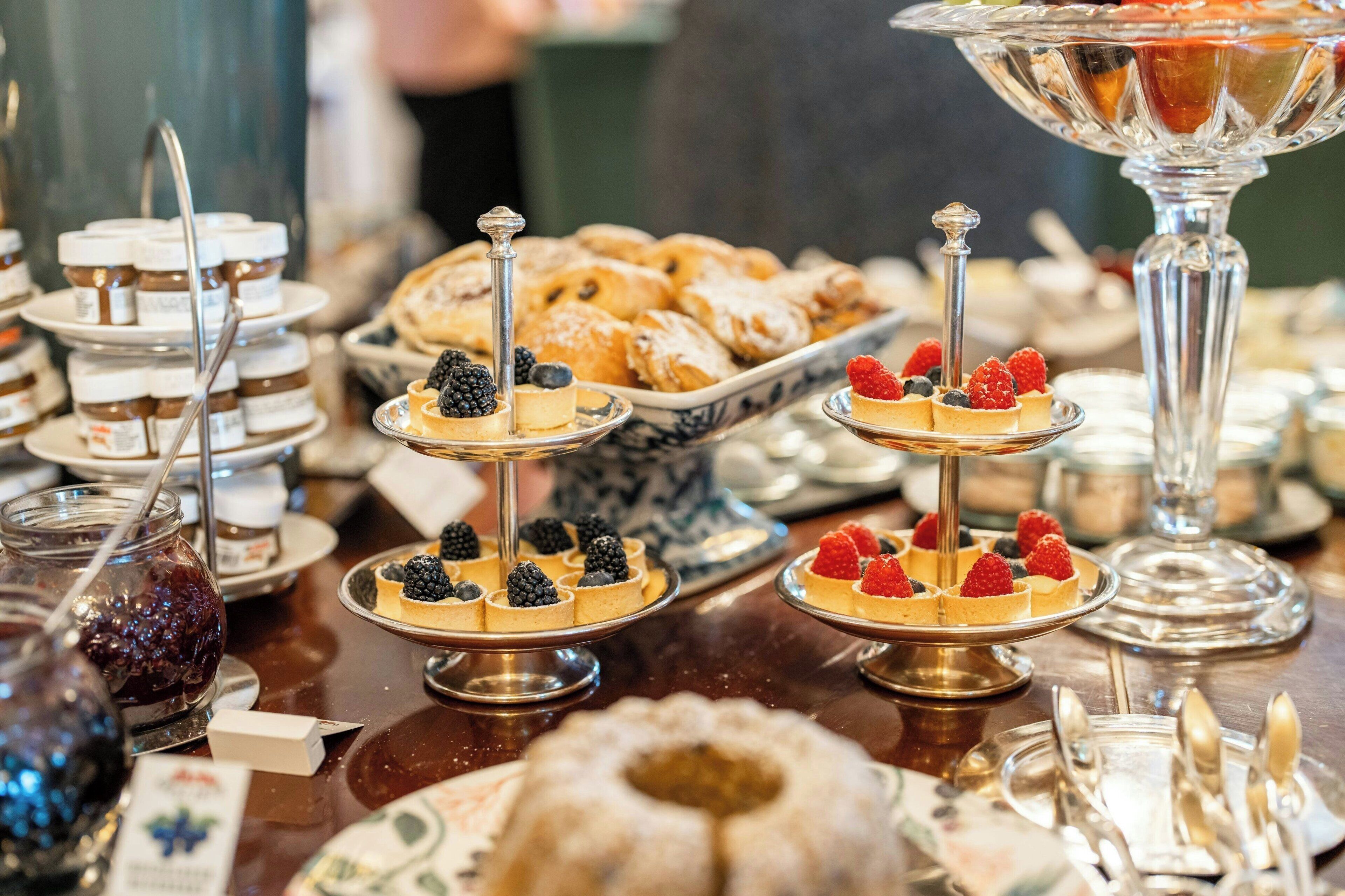 Ein Buffet mit verschiedenen Desserts und Gebäck, darunter Torten und Kuchen, auf mehreren Etageren präsentiert.