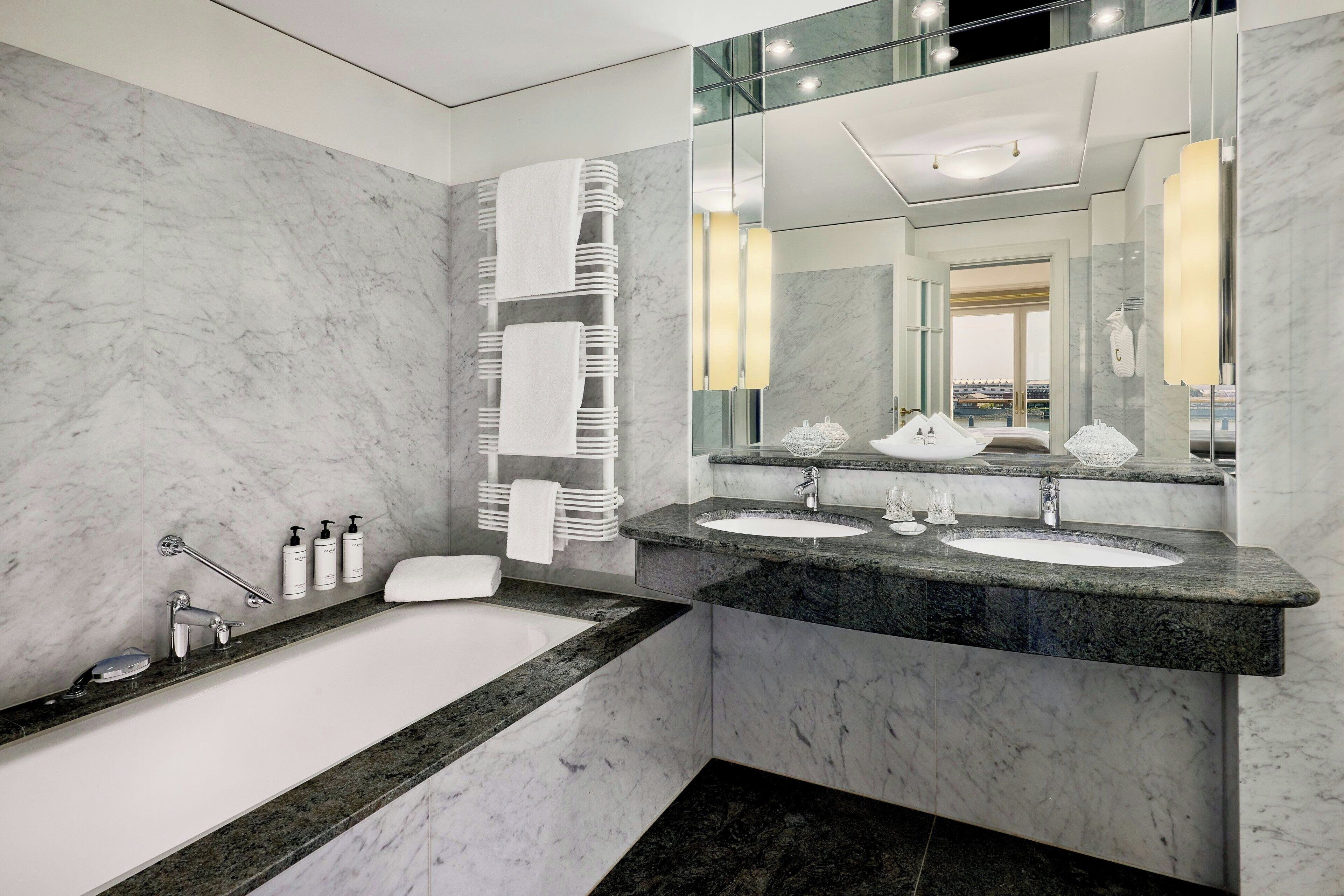 Ein modernes Badezimmer mit einer großzügigen Badewanne, zwei Waschbecken und einem großen Spiegel.