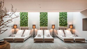 A spa room with six lounge chairs, a large plant wall, and floor lamps. - Louis C. Jacob, Hamburg, Autograph Collection (Hamburg)