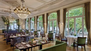 A spacious dining area with multiple tables and chairs, large windows with curtains, and a chandelier. - Louis C. Jacob, Hamburg, Autograph Collection (Hamburg)