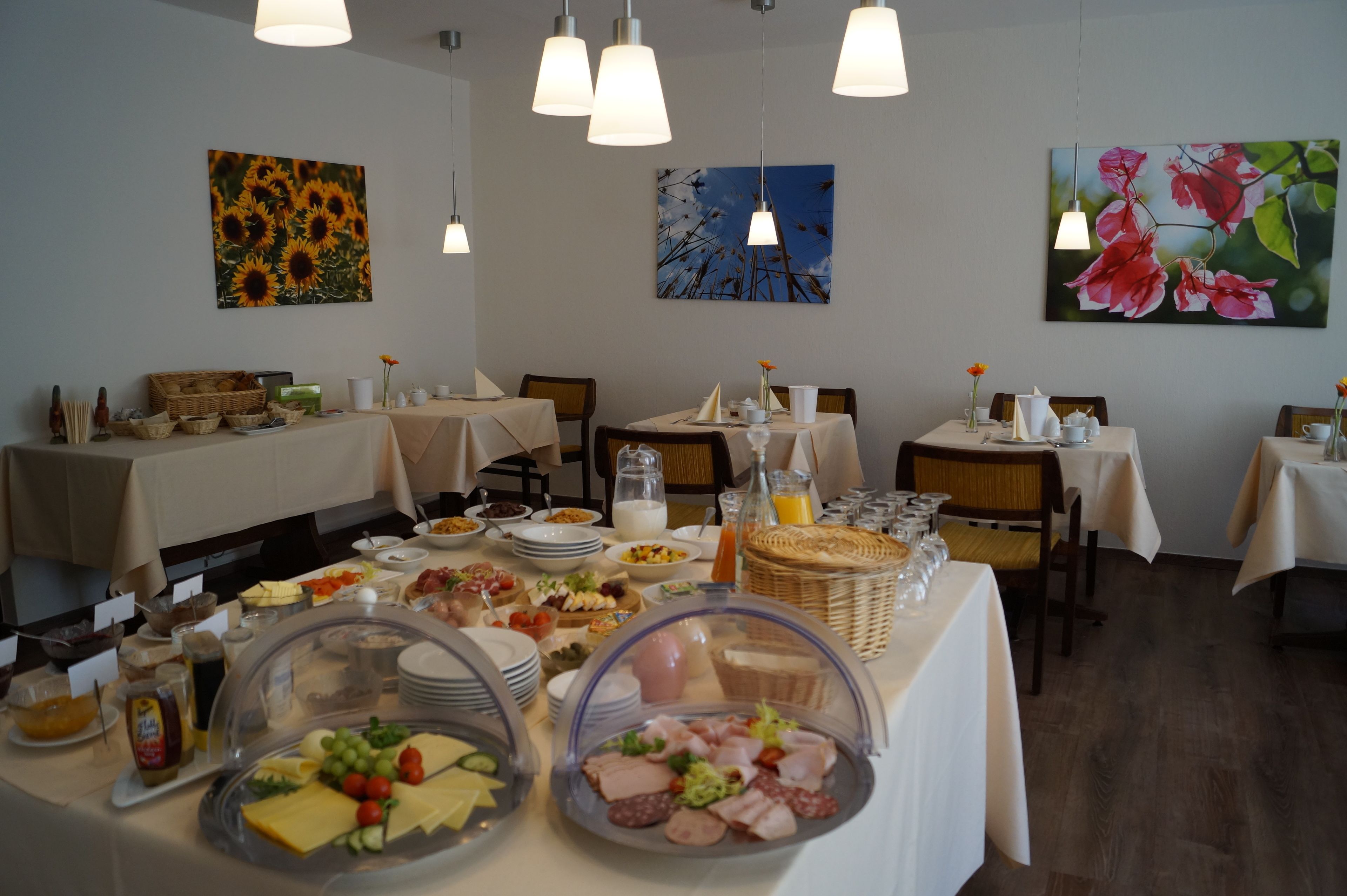 A breakfast buffet with various food items and drinks, arranged on tables with white tablecloths.