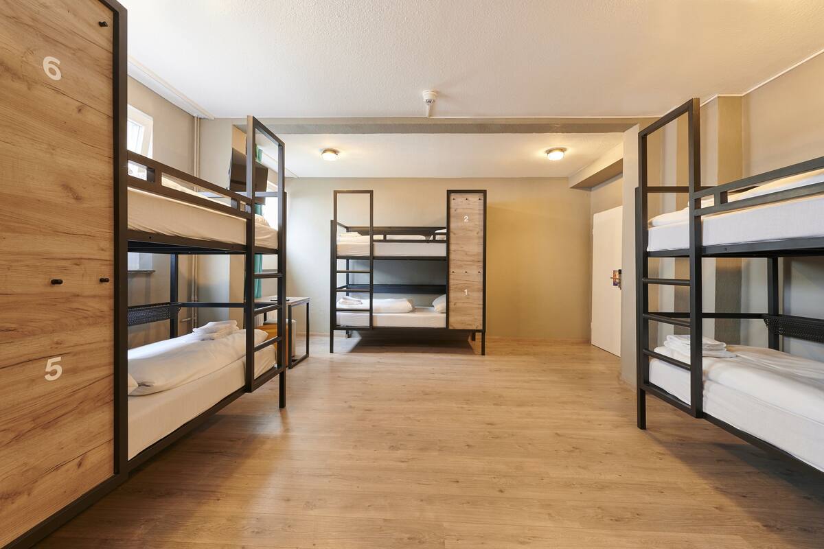 A room with bunk beds, wooden walls, and a ceiling fan.