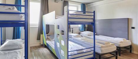 Un dormitorio con literas, una ventana con cortinas y un radiador.