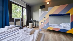 A hotel room with two beds, a television, and a window with curtains.