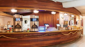 A wooden reception desk with a coffee machine, a digital screen, and a cash register.
